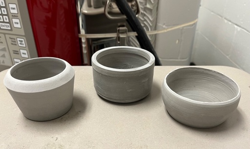 Three small earthenware clay bowls placed next to a kiln